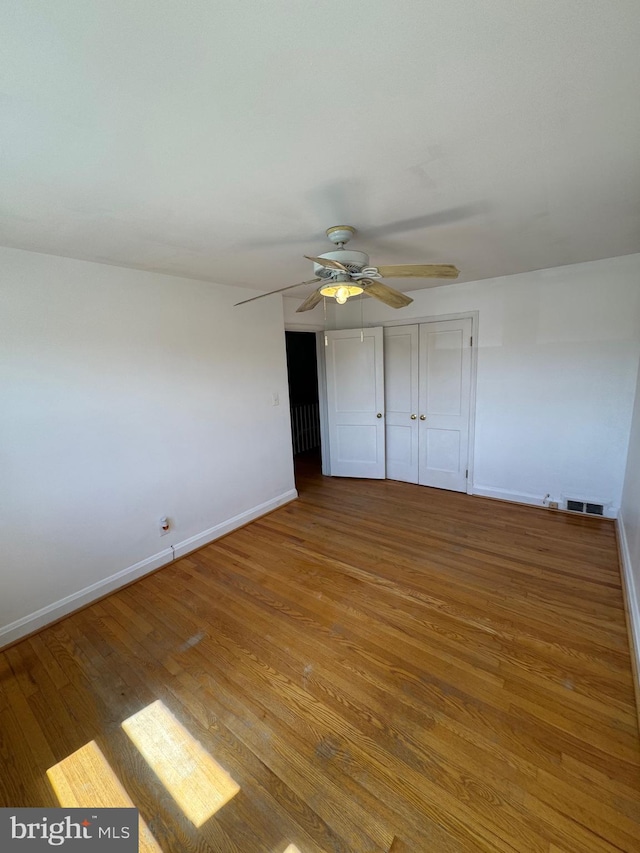 unfurnished bedroom with visible vents, baseboards, ceiling fan, and wood finished floors