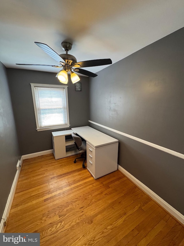 unfurnished office with wood finished floors, baseboards, and a ceiling fan