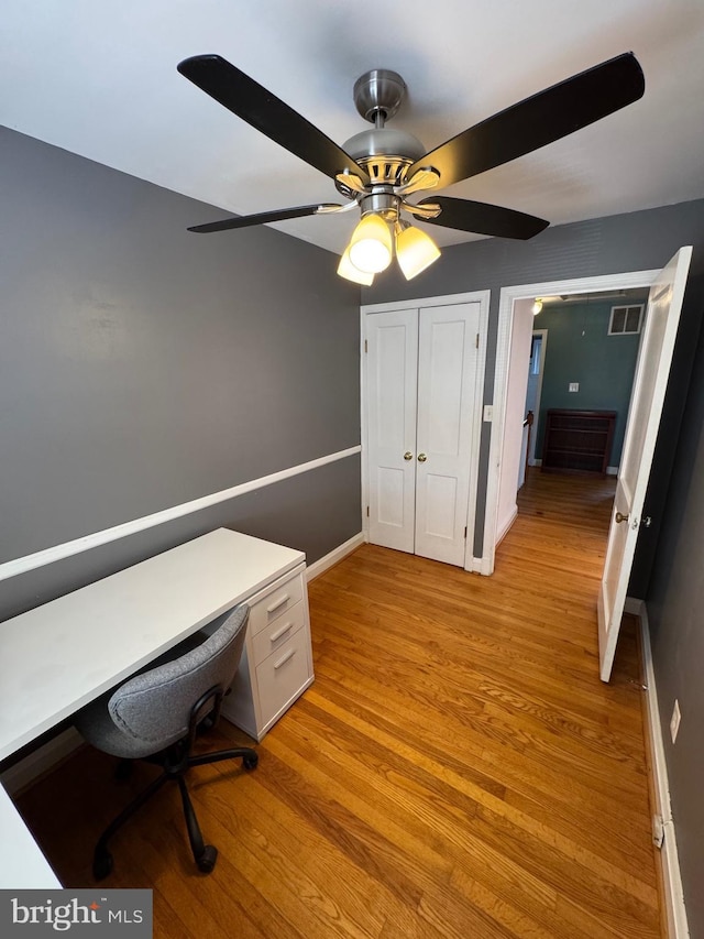 unfurnished office with light wood finished floors, visible vents, baseboards, and ceiling fan