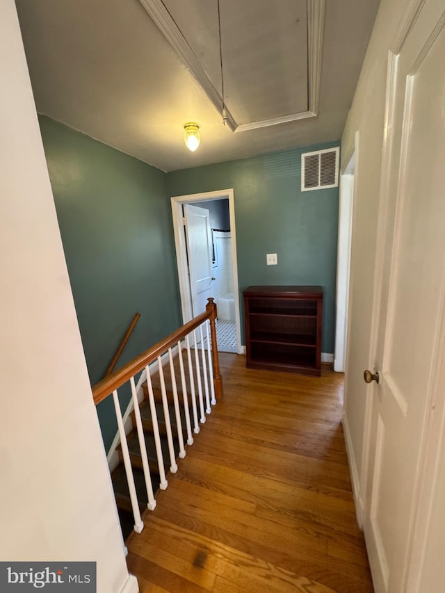 stairway with visible vents, attic access, and wood finished floors