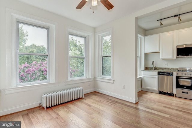 1674 Irving St NW, Washington, DC 20010 - kitchen featuring radiator, light stone countertops, white cabinets, light wood finished floors, and stainless steel appliances