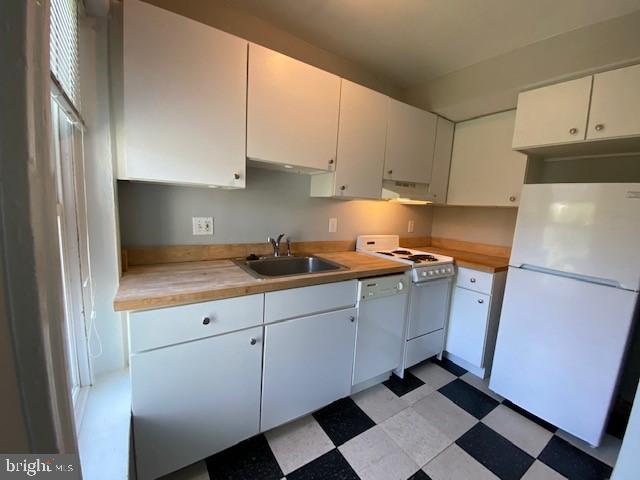 1674 Irving St NW, Washington, DC 20010 - kitchen featuring white appliances, light floors, white cabinetry, under cabinet range hood, and a sink