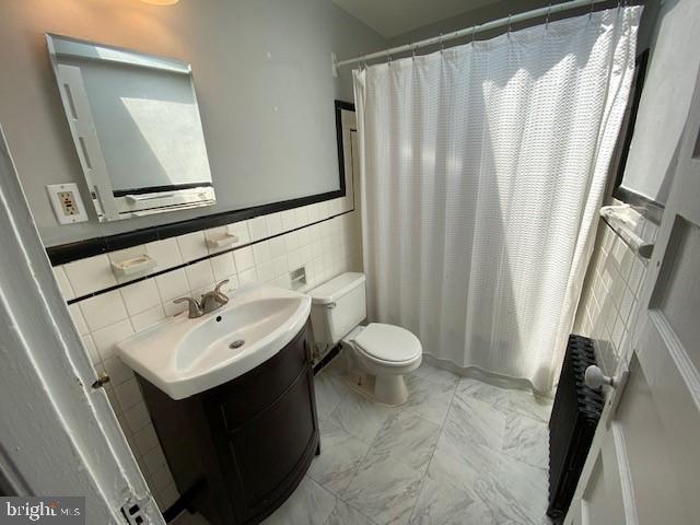 1674 Irving St NW, Washington, DC 20010 - bathroom featuring vanity, toilet, marble finish floor, tile walls, and curtained shower