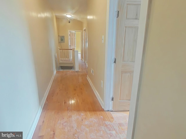 corridor featuring an upstairs landing, baseboards, and light wood-type flooring