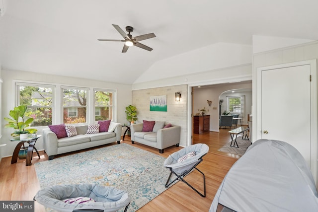 living area with light wood-style flooring, arched walkways, a ceiling fan, and a wealth of natural light