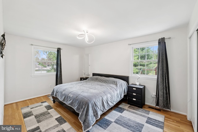 bedroom with visible vents, wood finished floors, and baseboards