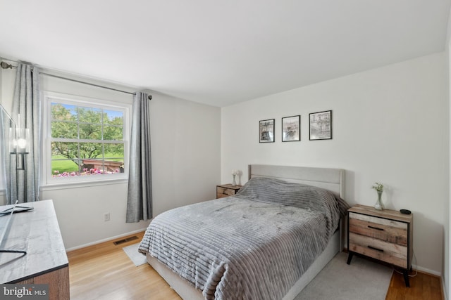 bedroom featuring visible vents, light wood-style flooring, and baseboards