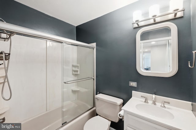 bathroom with toilet, combined bath / shower with glass door, and vanity