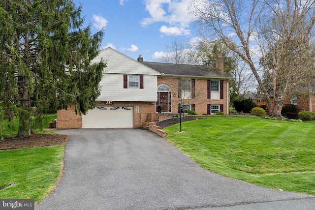 raised ranch with a front lawn, an attached garage, aphalt driveway, and a chimney
