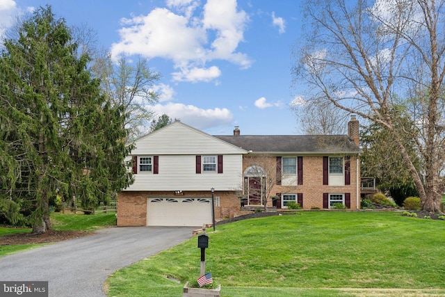 split foyer home featuring a front lawn, a chimney, aphalt driveway, and an attached garage