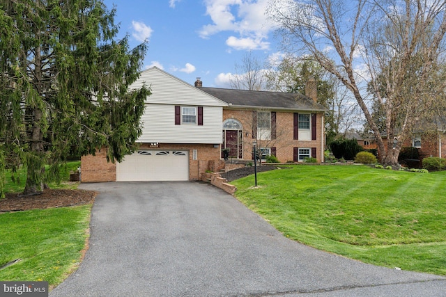 raised ranch with brick siding, a garage, aphalt driveway, and a chimney