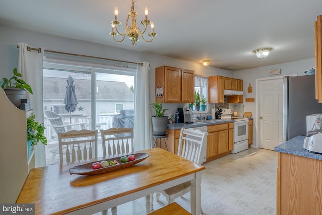 103 N Spinnaker Ln, Milton, DE 19966 - kitchen with white range with electric cooktop, freestanding refrigerator, under cabinet range hood, a sink, and a chandelier