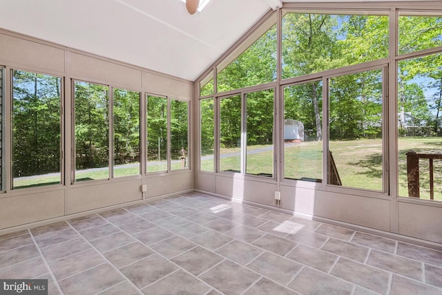 unfurnished sunroom featuring vaulted ceiling and view of wooded area