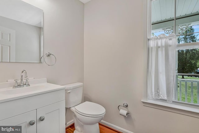 bathroom with wood finished floors, toilet, vanity, and baseboards