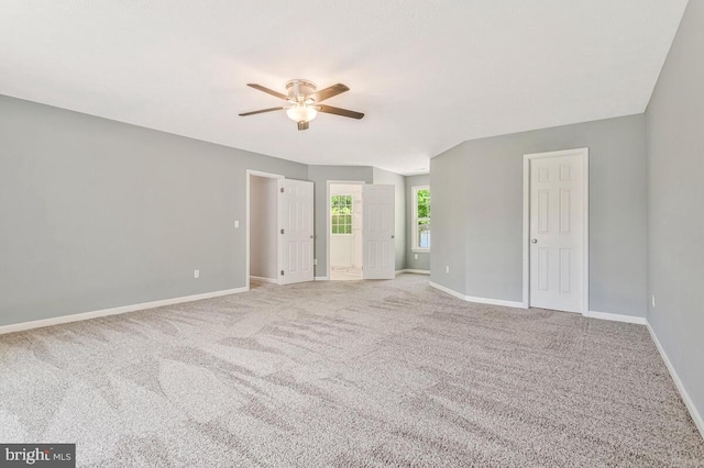 carpeted empty room featuring a ceiling fan and baseboards