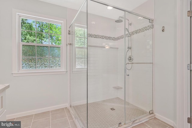 bathroom with baseboards, a shower stall, and tile patterned flooring