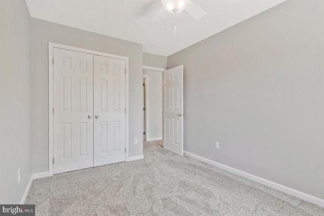 unfurnished bedroom with a closet, baseboards, carpet flooring, and ceiling fan