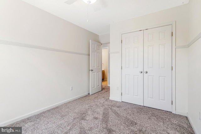 unfurnished bedroom with carpet, a closet, baseboards, and ceiling fan