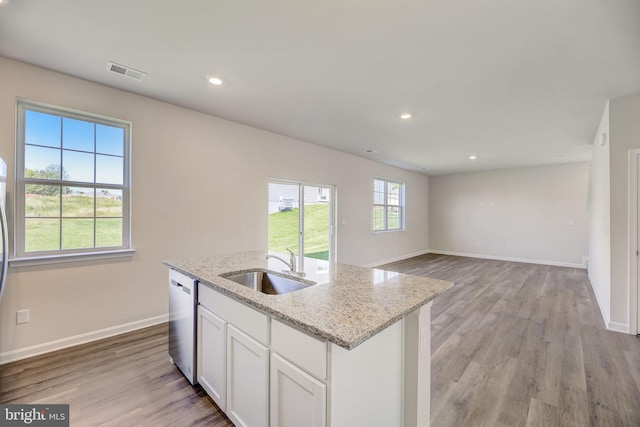 kitchen with light wood-style flooring, visible vents, white cabinets, a sink, and stainless steel dishwasher