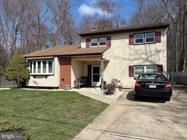 view of front of property with a shingled roof, concrete driveway, fence, and a front lawn
