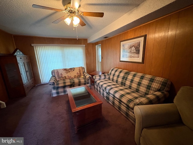 living room with a textured ceiling, wood walls, ceiling fan, and carpet floors