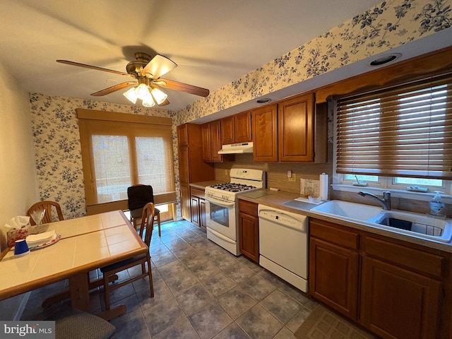 kitchen with a sink, ceiling fan, white appliances, under cabinet range hood, and wallpapered walls
