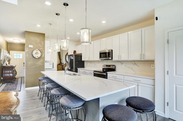 18010 Dave Anne Cir, Stewartstown, PA 17363 - kitchen featuring appliances with stainless steel finishes, a large island, light wood-type flooring, a kitchen breakfast bar, and light countertops