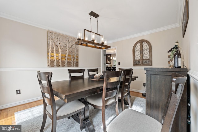 dining room with baseboards, ornamental molding, an inviting chandelier, and wood finished floors