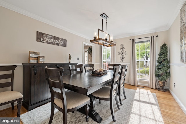 dining room featuring a chandelier, light wood-style flooring, visible vents, and ornamental molding