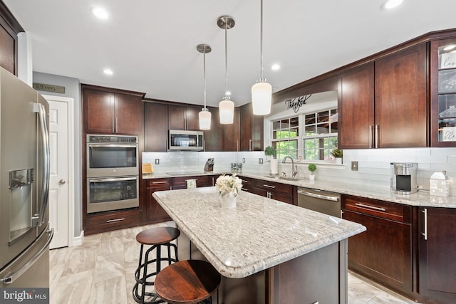 kitchen with marble finish floor, a breakfast bar, a sink, backsplash, and appliances with stainless steel finishes