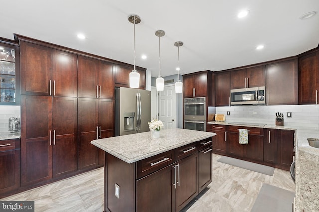 kitchen with a kitchen island, appliances with stainless steel finishes, decorative backsplash, and light stone countertops
