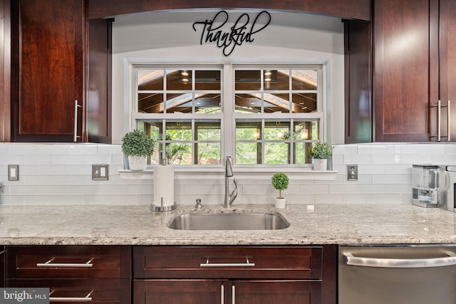kitchen featuring a sink, dark brown cabinetry, decorative backsplash, stainless steel dishwasher, and light stone countertops