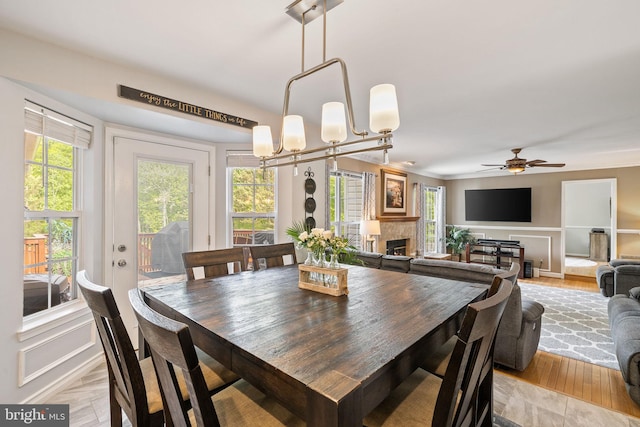 dining room featuring light wood-type flooring, a fireplace, and a ceiling fan