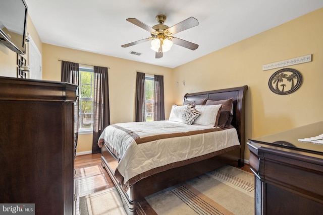 bedroom featuring baseboards, ceiling fan, light wood-style floors, and visible vents