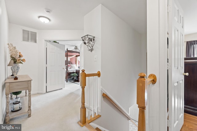 hall featuring light carpet, baseboards, an upstairs landing, and visible vents