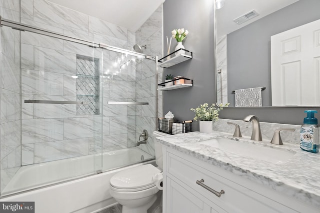 bathroom featuring toilet, vanity, visible vents, and bath / shower combo with glass door