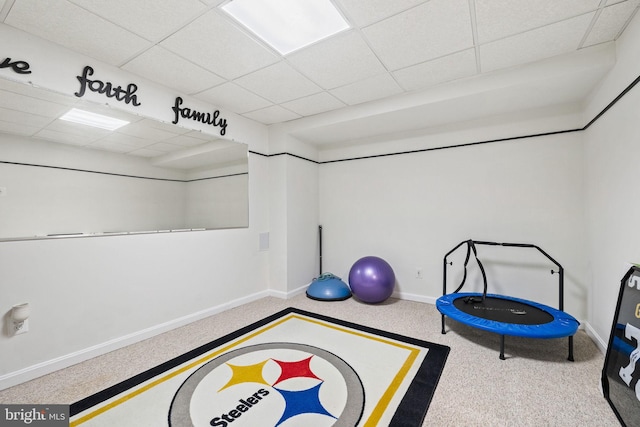 workout area featuring baseboards, a drop ceiling, and carpet flooring