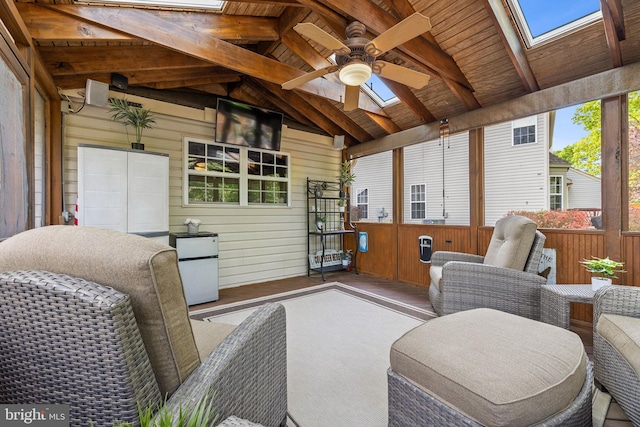sunroom / solarium with a ceiling fan, beam ceiling, and a skylight
