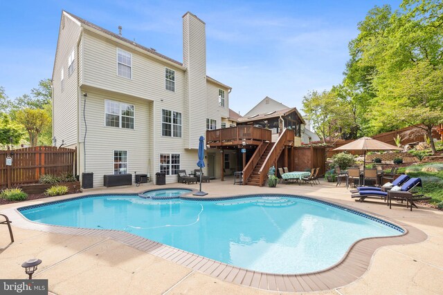view of swimming pool with a patio, an in ground hot tub, a wooden deck, stairway, and a fenced backyard