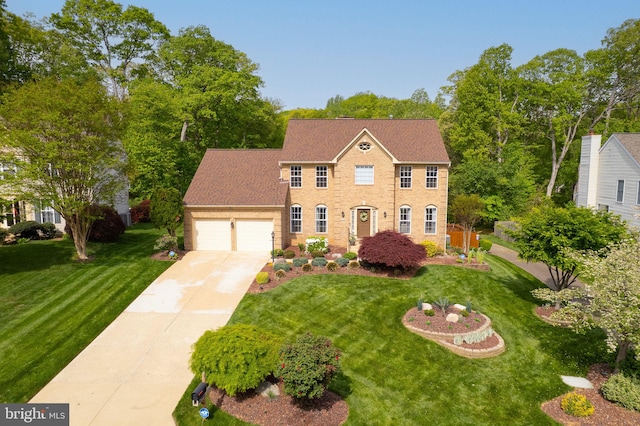 colonial house featuring an attached garage, driveway, and a front yard