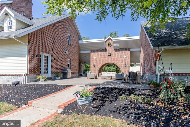 exterior space featuring brick siding, an outdoor living space, and a patio area