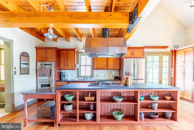 kitchen with appliances with stainless steel finishes, island exhaust hood, open shelves, and a center island