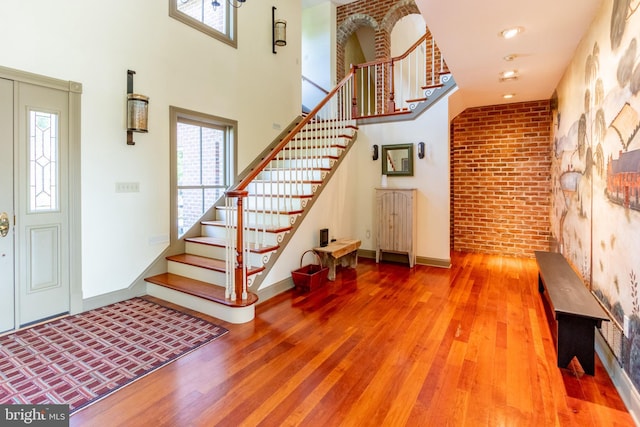 foyer featuring a wealth of natural light, wood finished floors, stairway, and baseboards