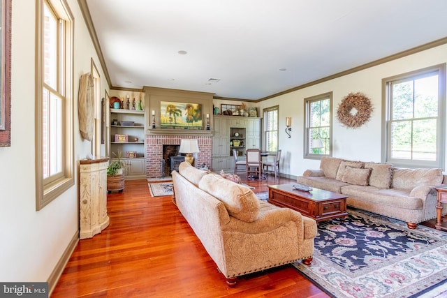 living area with a fireplace, wood finished floors, ornamental molding, and baseboards