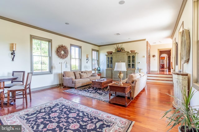 living room featuring visible vents, crown molding, light wood-style flooring, and baseboards