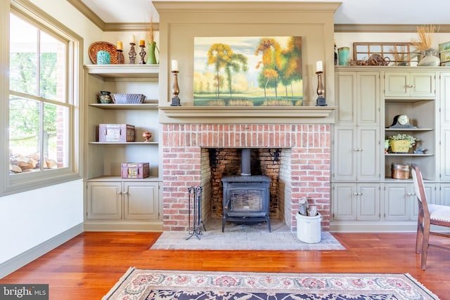 living area with crown molding, a wood stove, a wealth of natural light, and light wood-style floors