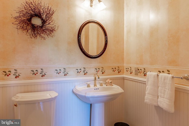 half bathroom featuring toilet and a wainscoted wall