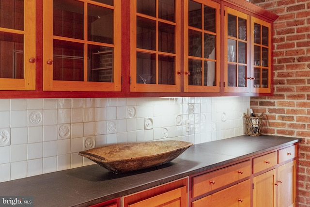 kitchen with dark countertops, glass insert cabinets, and backsplash