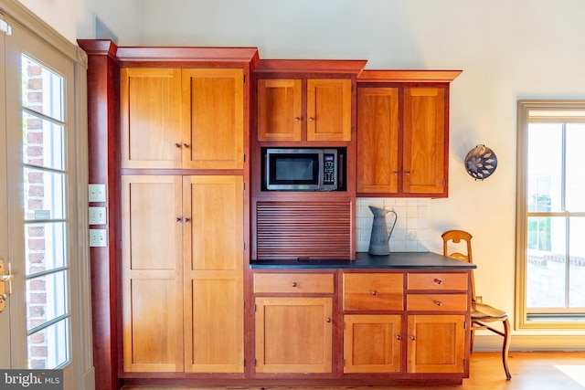 kitchen featuring a healthy amount of sunlight, backsplash, and stainless steel microwave