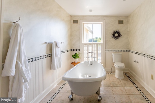 full bath featuring toilet, visible vents, a soaking tub, and tile patterned flooring